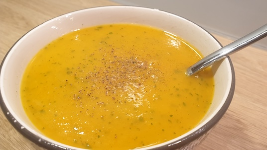 Bol de velouté de carottes au cumin saupoudré d'épices