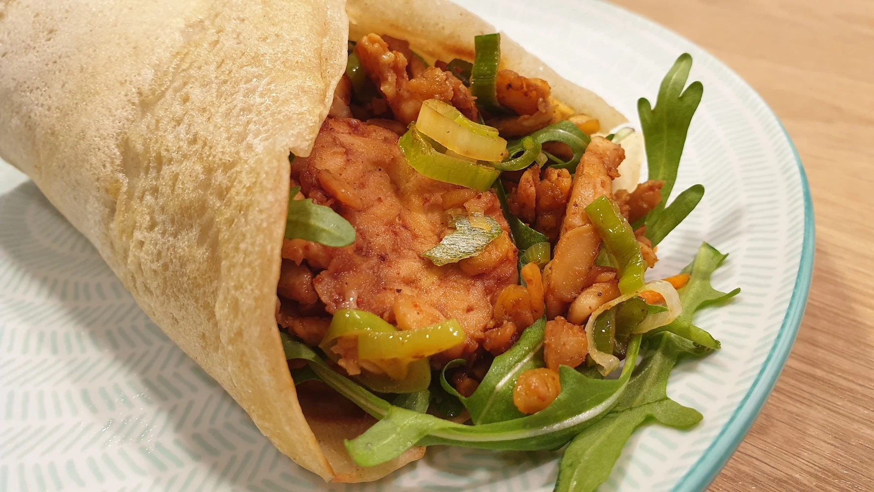 Wrap fait maison garni de tempeh grillé, carottes râpées et roquette